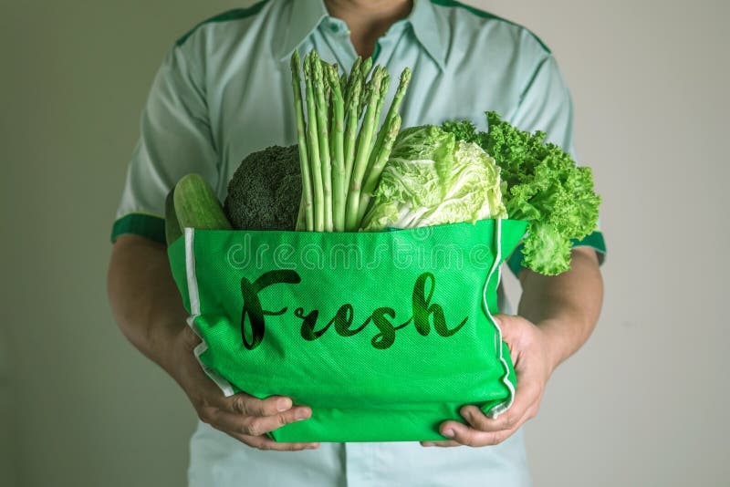 close up hand holding green grocery bag of mixed the organic green vegetables , healthy organic green food shopping and diet