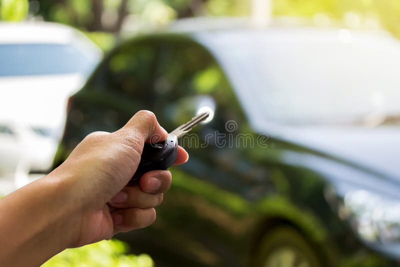Close up hand holding the keys over blurred of used car