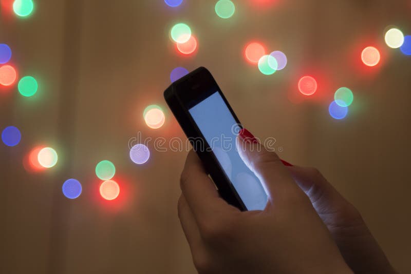 Close Up Of A Hand Holding Mobile Phone Christmas Bokeh Lights In The