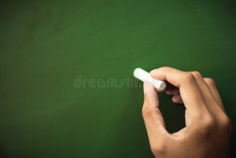 Close up ,Hand holding white chalk pointing something on chalkboard,Copy space for your text stock image