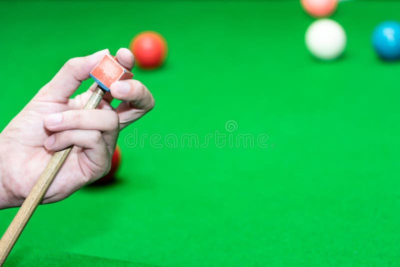 Close up hand player snooker using chalk rubbing a cue