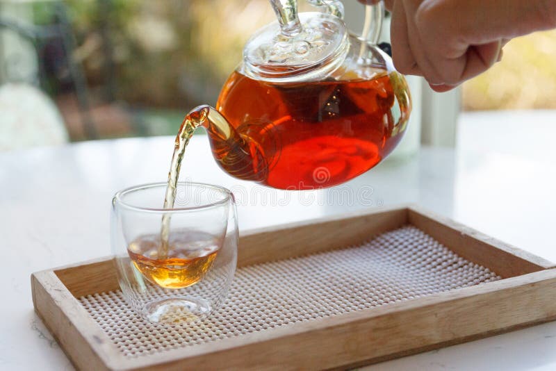 Close Up of the Hand Pouring Green Tea from Glass Kettle To Small Cup