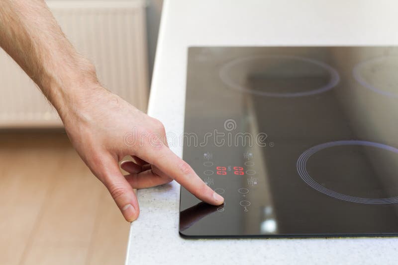 Close Up of Hand Turning on Ceramic Stove. Stock Image Image of
