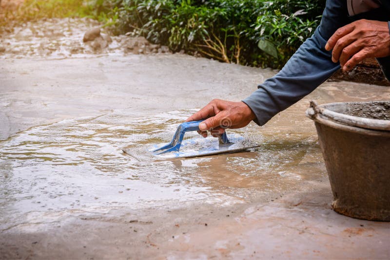Closeup of Hand Using Trowel To Finish Wet Concrete Floor Stock Photo