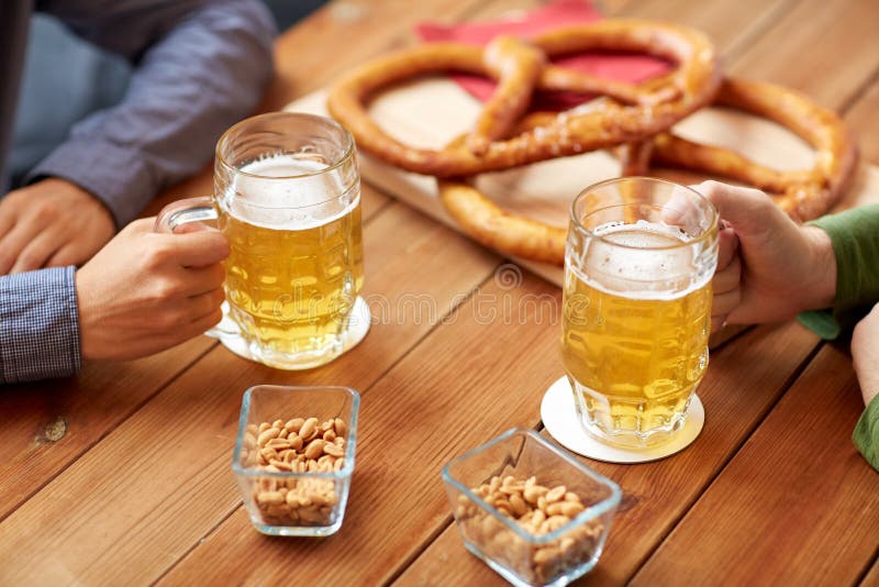 Close up of hands with beer mugs at bar or pub