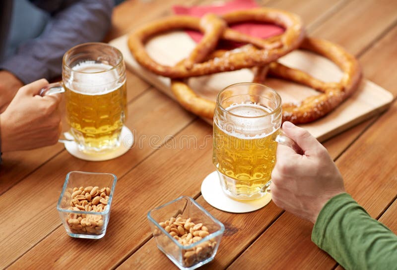 Close up of hands with beer mugs at bar or pub