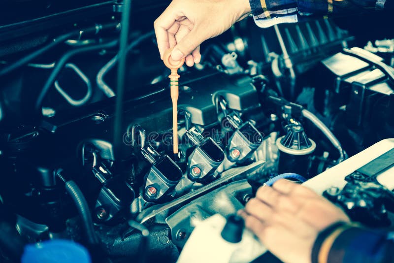Close up hands checking lube oil level of car engine from deep-stick for service and maintenance concept stock image Close up hands checking lube oil level of car engine from deep-stick for service and maintenance concept stock image