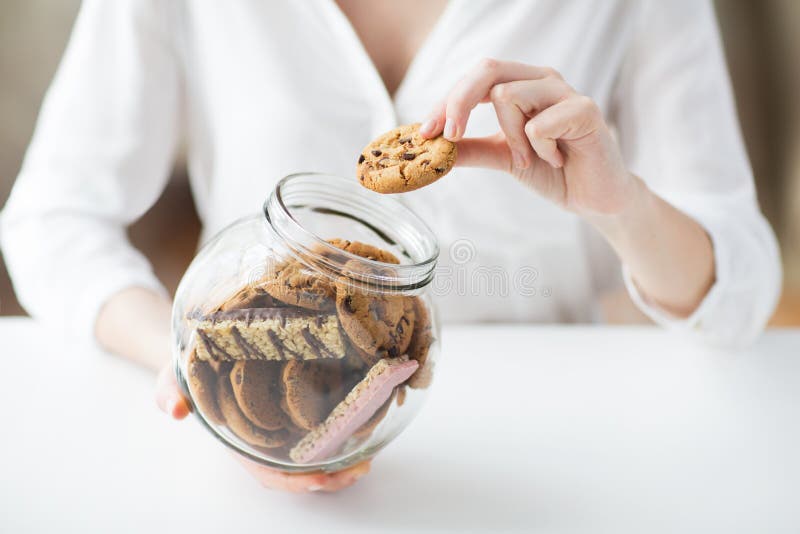 Close up of hands with chocolate cookies in jar