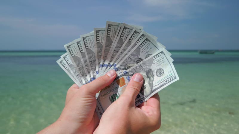 Close-up of hands holding US dollar bills on tropical beach stock video