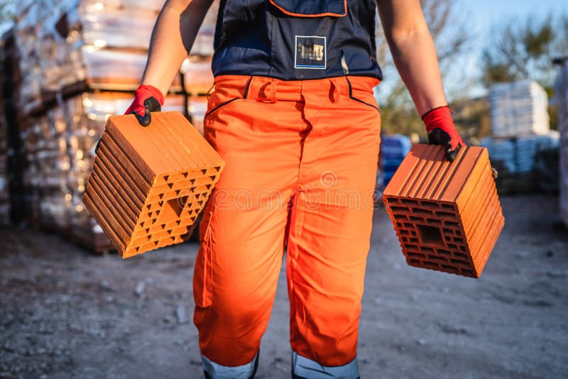 Close up on hands and midsection of unknown man construction worker taking orange hollow clay blocks ar warehouse or construction stock images