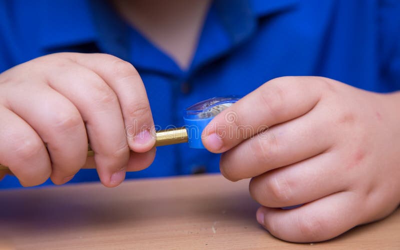 Close-up hands of a student turn a pencil in a sharpener. stock image