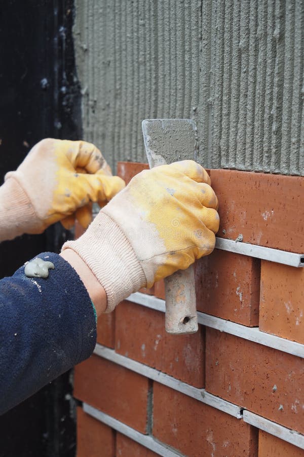 A Bricklayer is Seen Applying Mortar on a Wall As Part of the Building