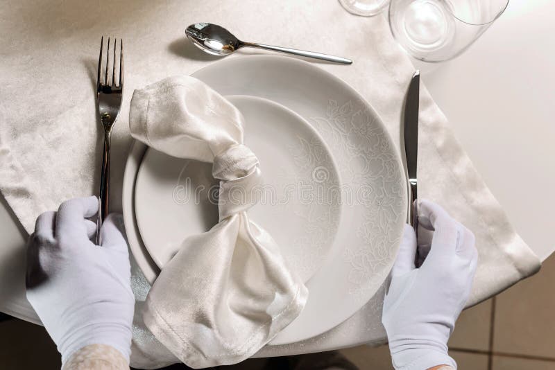 Closeup of Hands in White Gloves Serving Dinner Table Stock Photo