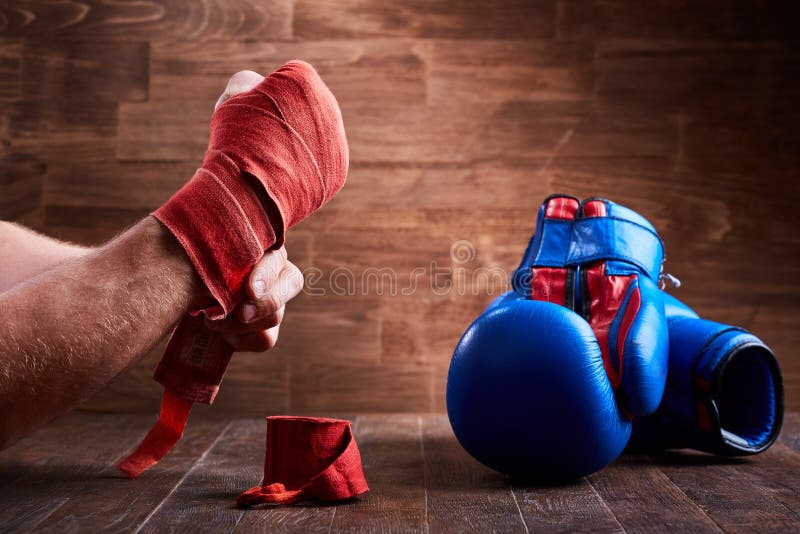 Close-up of the hands of a young boxer who winds boxing bandages and gloves.