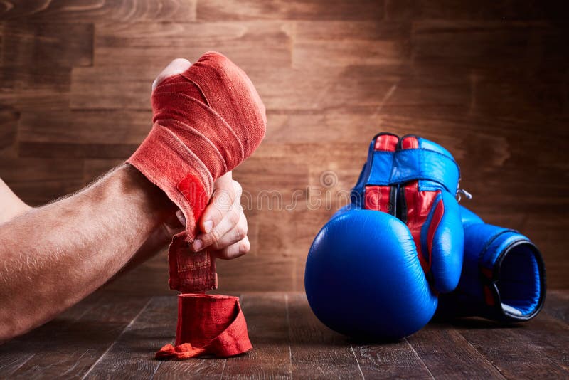 Close-up of the hands of a young boxer who winds boxing bandages and gloves.