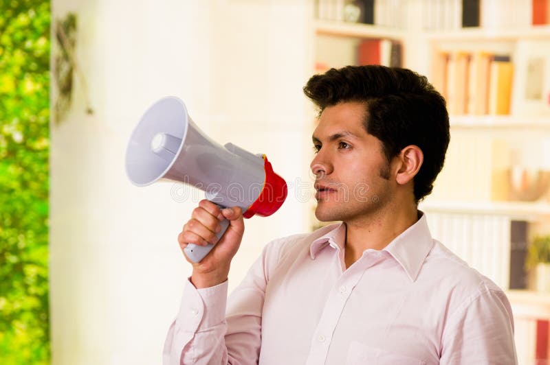 Close up of a handsome serious man holding a megaphone in his hand in a blurred background royalty free stock images Close up of a handsome serious man holding a megaphone in his hand in a blurred background royalty free stock images