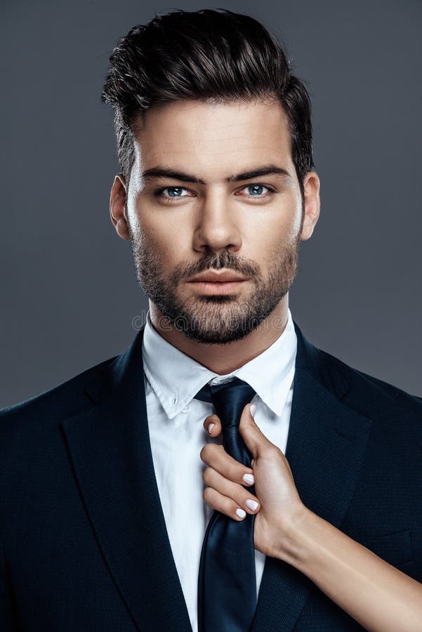 Close-up handsome and successful man in an expensive suit. He is in a white shirt with a tie.