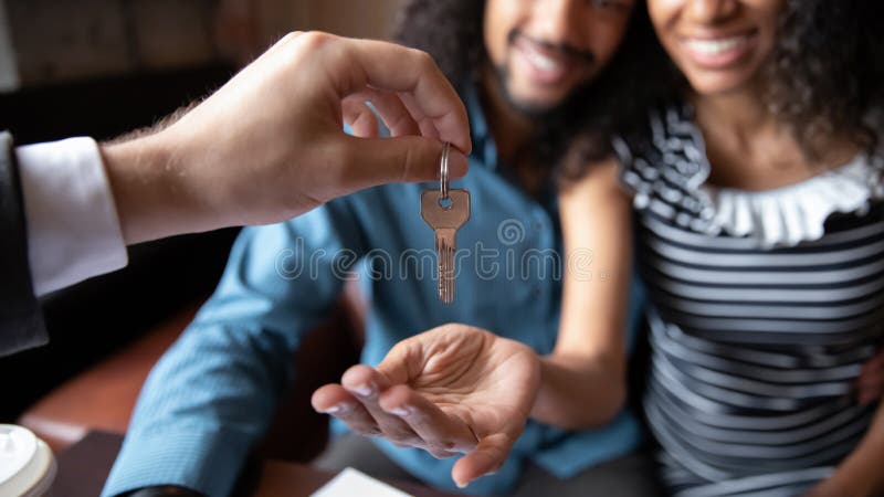 Close up happy African American couple receiving keys from realtor