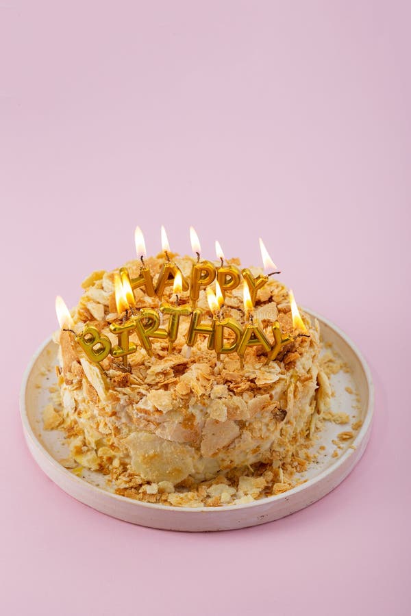 Close Up of Happy Birthday Cake with Burning Candles on Pink Surface