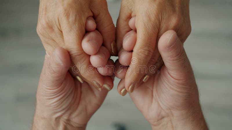 Close-up of happy couple holding hands, man is caressing woman's palms