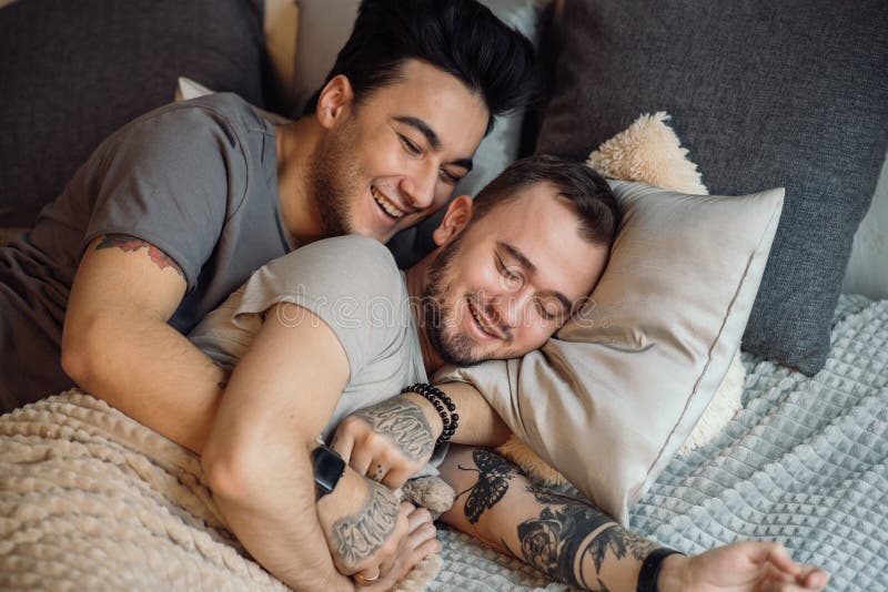 Close-up of happy gay couple sleeping in bed together. 