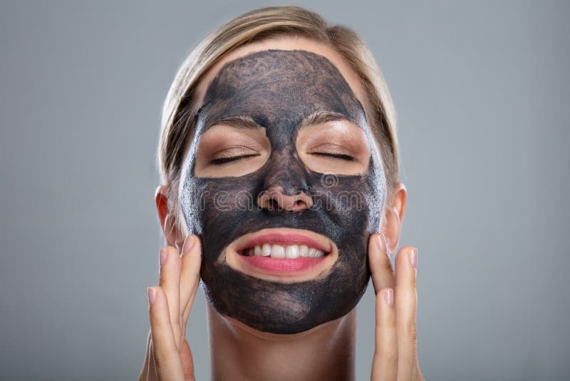 Happy Woman Using Activated Charcoal Face Mask royalty free stock images