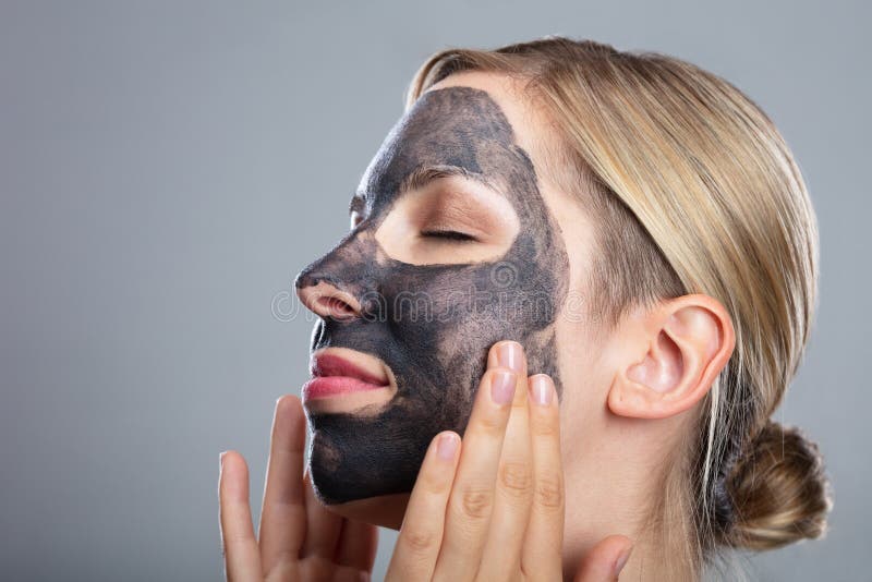 Happy Woman Using Activated Charcoal Face Mask royalty free stock image