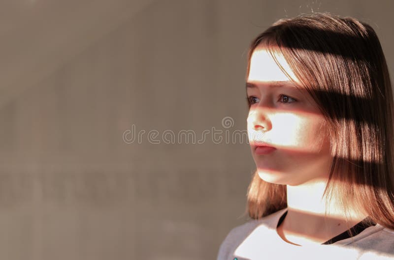 Close up hard light portrait of tween girl with stripe shadows on her face.