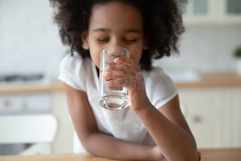 Close up head shot African American little girl drinking water