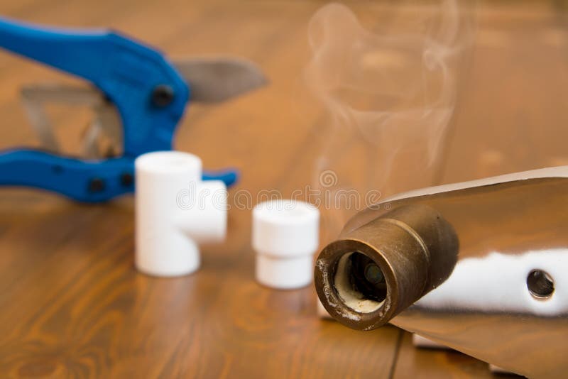 Close-up of a heated soldering iron with smoke from a melted plastic pipe, on a wooden background stock images Close-up of a heated soldering iron with smoke from a melted plastic pipe, on a wooden background stock images