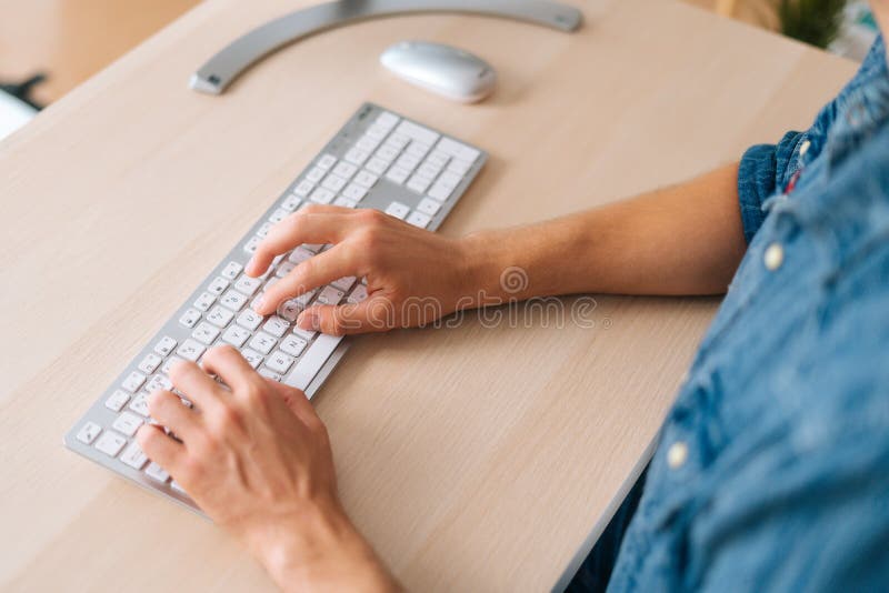Close-up high-angle view hands of unrecognizable young business man working typing online message using wireless computer keyboard, sitting at desk in home office room, selective focus.