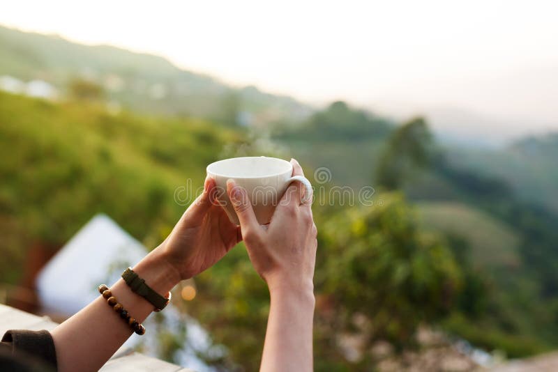 Hot drink coffee or tea on woman hand in the morning at outdoor cafe