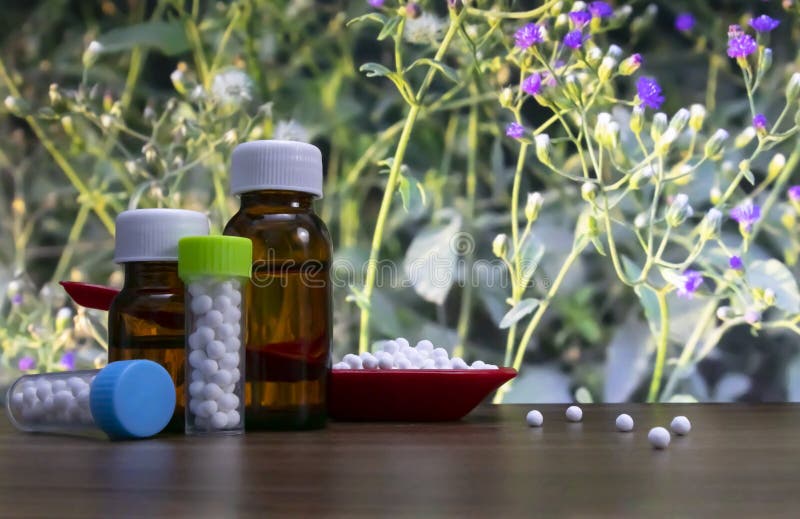 Close-up image of homeopathic pills in red spoon and bottle of liquid and globules substance with spread white sugar balls on wood royalty free stock photos Close-up image of homeopathic pills in red spoon and bottle of liquid and globules substance with spread white sugar balls on wood royalty free stock photos