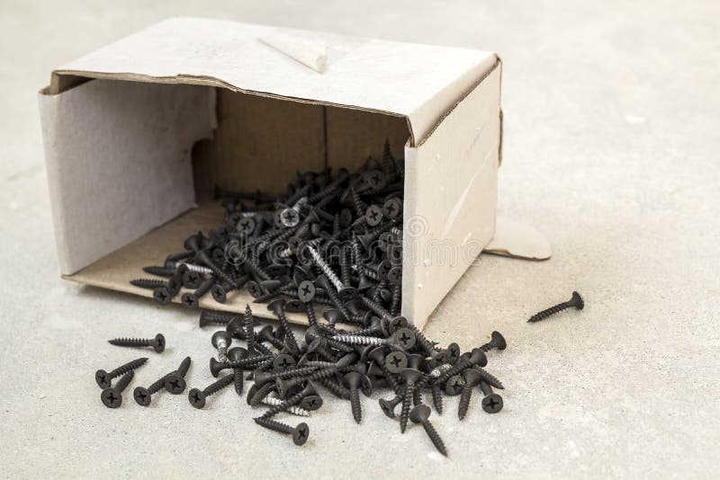 Closeup Image of Many Small Black Screws on Concrete Background Stock