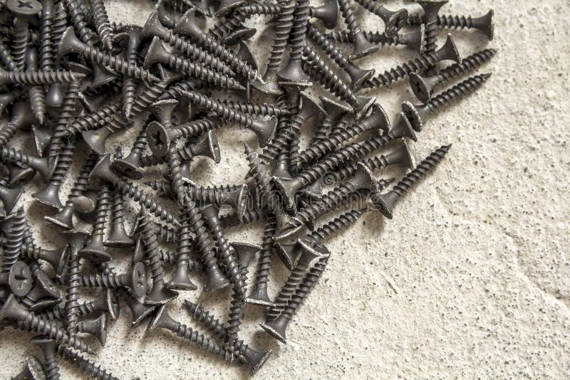 Closeup Image of Many Small Black Screws on Concrete Background Stock
