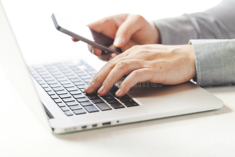 Close up image of multitasking business man using a laptop and mobile phone Close up image of multitasking business man using a laptop and mobile phone