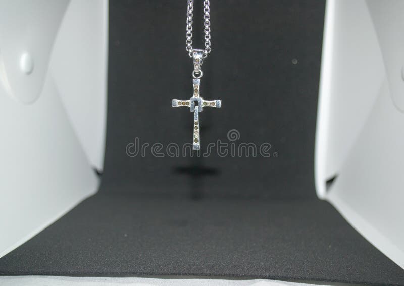 Close-up image of a silver metal christian cross necklace/pendant or silver metal crucifix necklace/pendant hanging stock photography