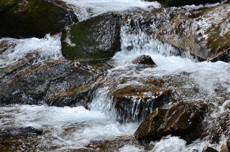 Close-up image of a small wild waterfall in the form of short streams of water between mountain stones royalty free stock photos Close-up image of a small wild waterfall in the form of short streams of water between mountain stones royalty free stock photos