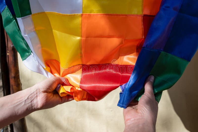 Close-up image of woman\'s hands clutching a silk Wiphala flag, a symbol commonly used to represent the native stock image