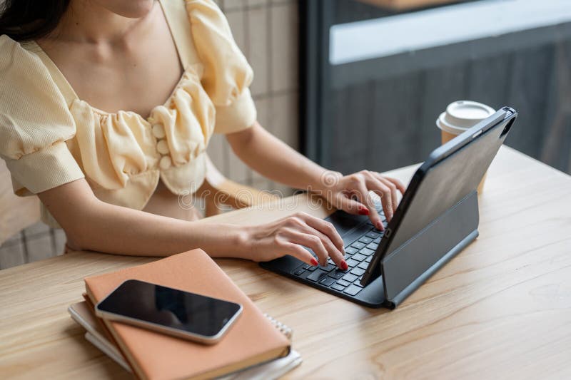 A close-up image of a woman using a digital tablet, typing on the wireless keyboard stock image