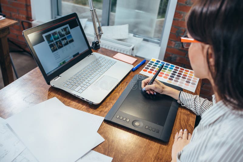 Close-up image of women drawing a project using a graphic tablet and a laptop sitting in modern office stock photos
