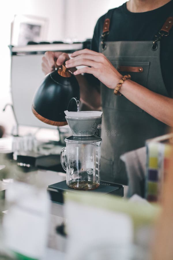 Close up image Young male barista pouring boiling water from kettle for filter coffee