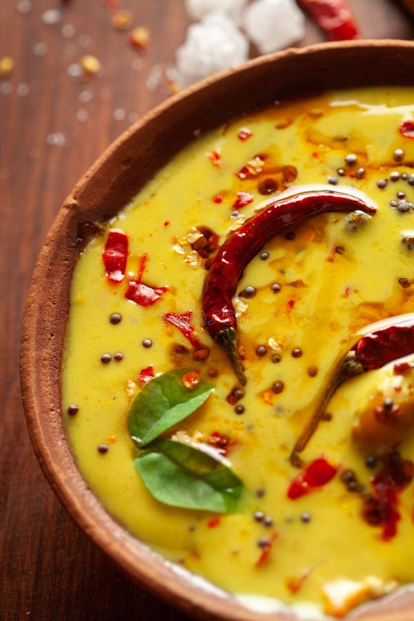 Close-up of Indian traditional kadhi or kadi pakora yogurt and gram flour and turmeric served hot in a clay bowl.