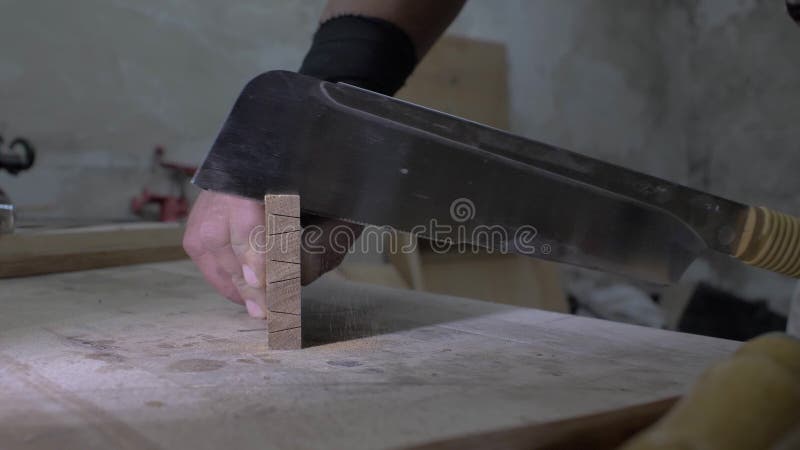 Close-up, joiner making a dovetail on a wooden detail. A carpenter saws a wooden oak board with a hand saw .4k. 4k video. slow