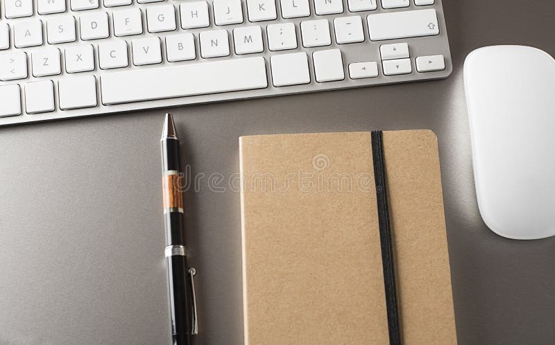 Close-up of keyboard, mouse, and pen with a notebook in the office
