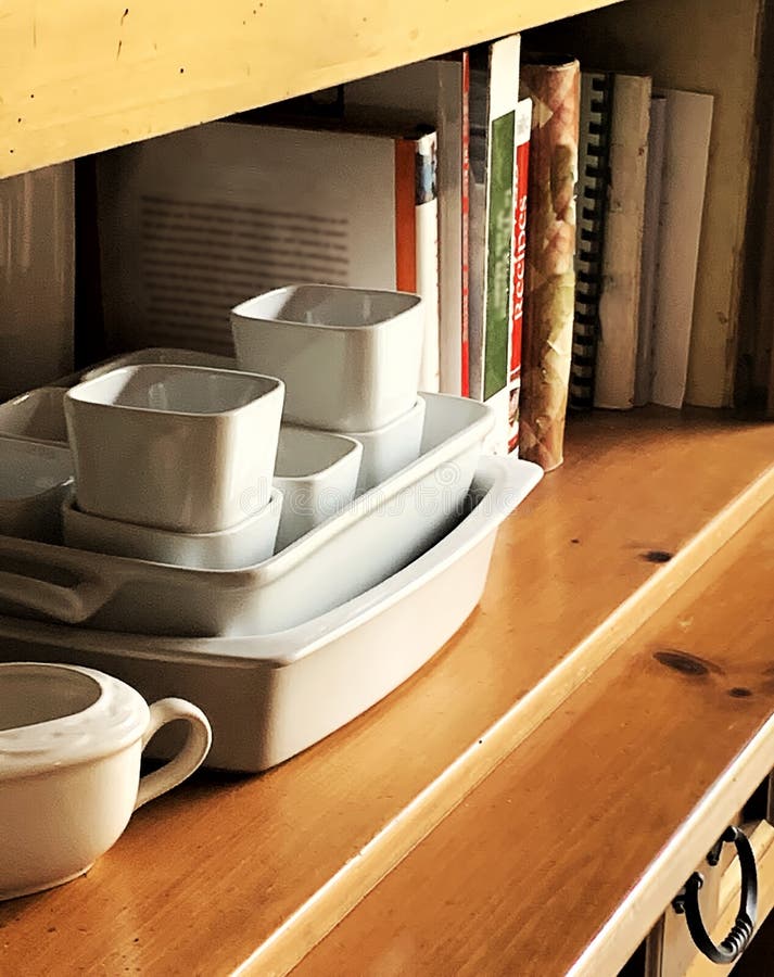 Close-up of kitchen country hutch with white dishes and cookbooks.  Image taken on slight angle.