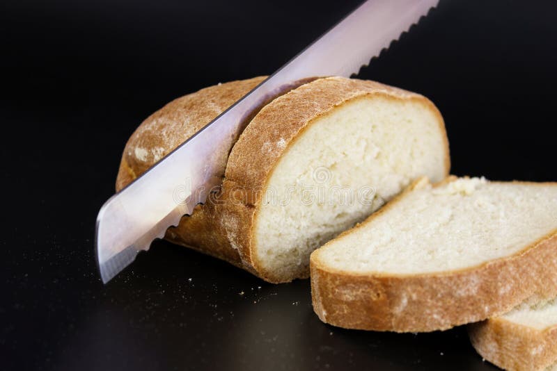 Close Up Large Knife Cuts Thin Pieces of White Bread from a Rectangular