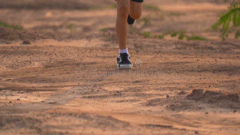 Close up leg of boy running on ground on light of sunset, kids jogging on rural countryside for good heath