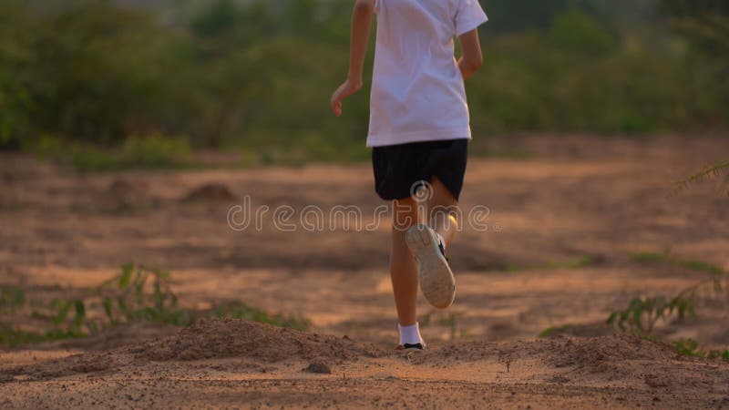 Close up leg of boy running on ground on light of sunset, kids jogging on rural countryside for good heath
