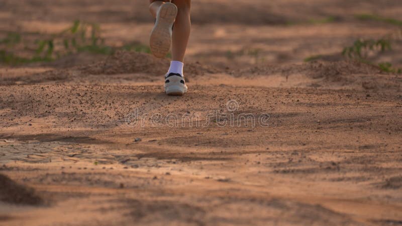 Close up leg of boy running on ground on light of sunset, kids jogging on rural countryside for good heath